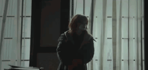 Woman in Mask in Dark Room by Window