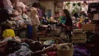 Woman in Messy Room With Pile of Clothes