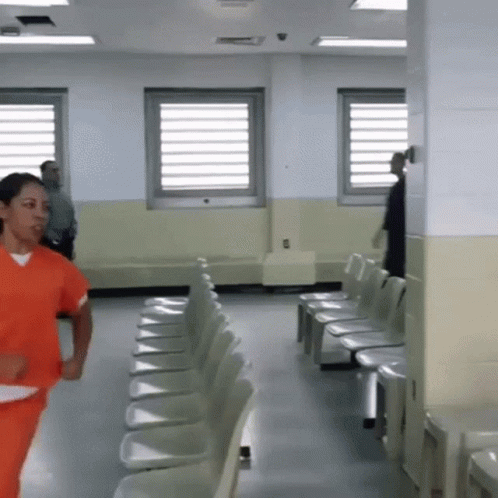 Woman In Orange Scrubs Running Through Chairs GIF