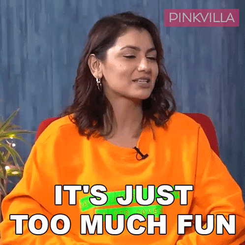 Woman In Orange Shirt Sitting Saying It's Just Too Much Fun GIF