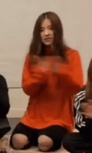 Woman In Orange Sweater Sitting GIF