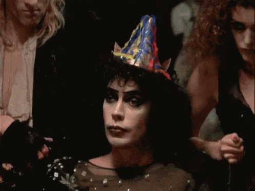 Woman In Party Hat In Dark Room With Others GIF