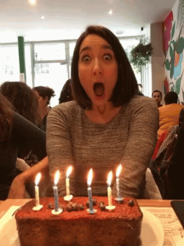 Woman In Party Hat Smiling Holding Candle GIF