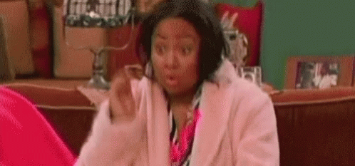 Woman In Pink Coat Surprised On Couch GIF