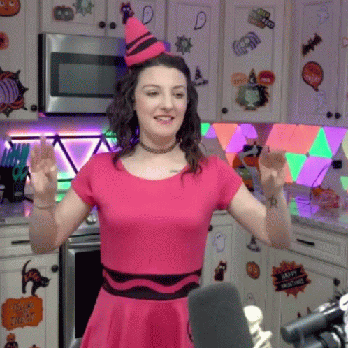 Woman in Pink Dress and Crayon Hat Standing in Kitchen