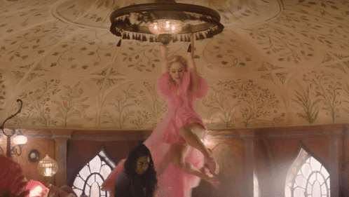 Woman in Pink Dress Flying Before Chandelier