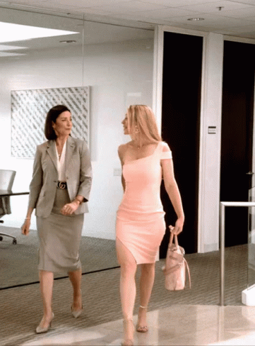 Woman in Pink Dress Walking Beside Grey Suit