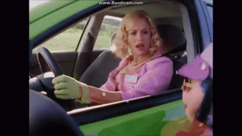 Woman in Pink Driving Green Car Talks to Purple Hat Man