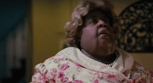 Woman In Pink Floral Dress And Pearls On Bed GIF