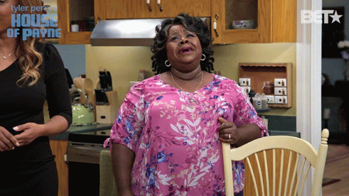 Woman in Pink Floral Shirt Sitting in Kitchen with House of Payne Logo