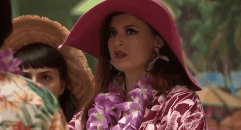 Woman In Pink Hat And Lei Standing In Crowd GIF
