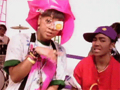 Woman in Pink Hat and Sunglasses Next to Woman in Red Shirt