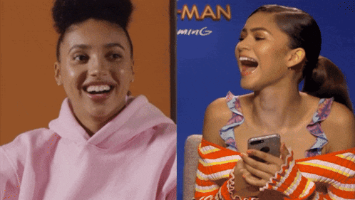 Woman In Pink Hoodie Laughing Next To Woman In Orange Sweater GIF