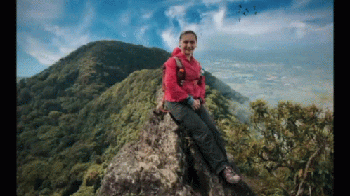 Woman In Pink Jacket Sitting On Rocky Mountain GIF