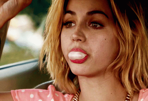 Woman in Pink Polka Dot Top Blowing Bubble Gum