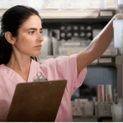 Woman in Pink Scrubs Reaching for Bottle