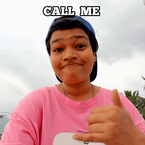 Woman in Pink Shirt and Blue Hat Thumbs Up Saying Call Me