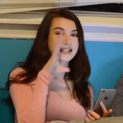 Woman In Pink Shirt Holding Phone Making Funny Face GIF