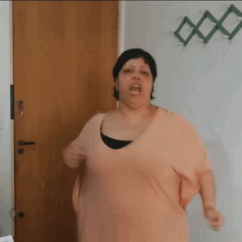 Woman In Pink Shirt Standing In Front Of Door GIF