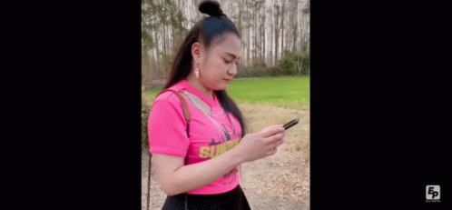 Woman In Pink Shirt Standing On Dirt Road In Field GIF