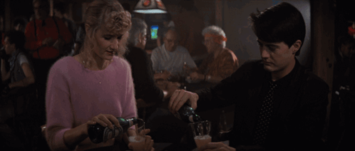 Woman in Pink Sweater Holding Beer Next to Man in Black Shirt