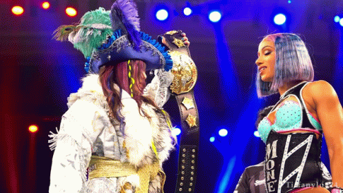 Woman In Pirate Costume Holding Championship Belt Next To Another Woman GIF