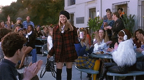 Woman in Plaid Dress and Beret Before Applauding Crowd