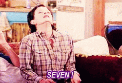 Woman in Plaid Shirt Says Purple Seven on Couch