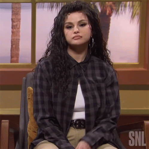 Woman In Plaid Shirt Sitting In Front Of SNL Logo GIF