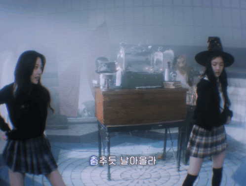Woman in Plaid Skirt and Witch Hat Next to Another Woman