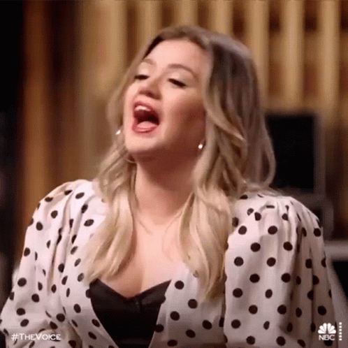 Woman in Polka Dot Shirt Singing With Mouth Open