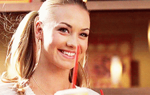 Woman in Ponytail Smiling and Drinking From Cup With Red Straw