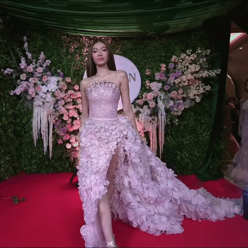 Woman in Purple Dress on Red Carpet in Front of Flowers