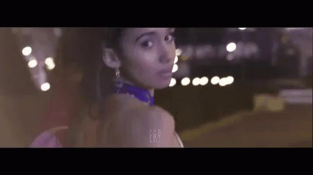 Woman in Purple Dress Standing in Front of Blurry Lights