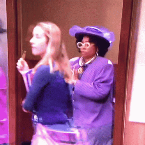 Woman In Purple Hat Next To Woman In Blue Shirt GIF
