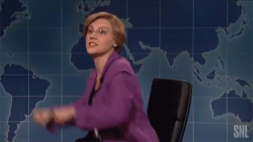Woman In Purple Jacket Next To Man In Suit And Tie On SNL GIF