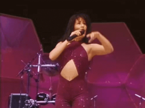 Woman in Purple Jumpsuit Singing Into Microphone