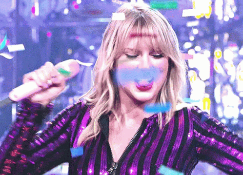 Woman in Purple Sequined Top Blowing Confetti With Microphone