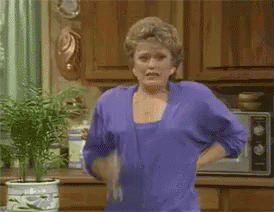 Woman In Purple Shirt Holding Towel In Kitchen GIF