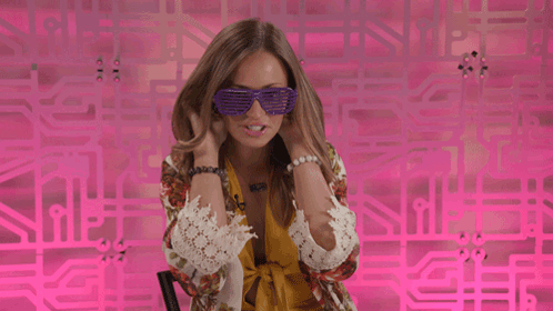 Woman In Purple Sunglasses In Front Of Pink Wall GIF