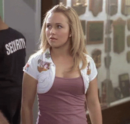 Woman In Purple Tank Top And White Jacket Standing In Front Of Man In Security Shirt GIF