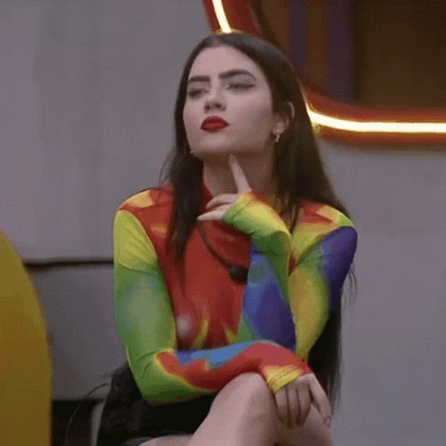 Woman in Rainbow Shirt Sitting With Hand on Chin