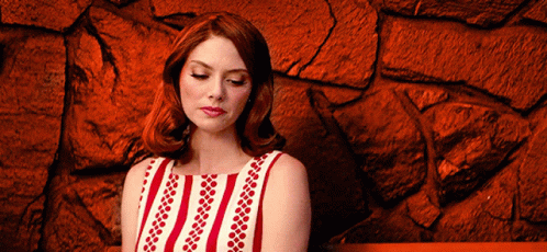 Woman in Red and White Striped Dress Sitting by Red Stone Wall