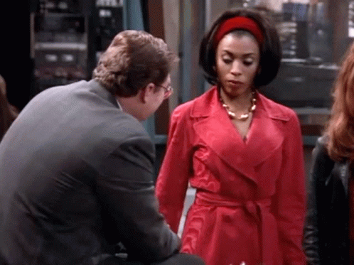 Woman In Red Coat Talking To Man GIF