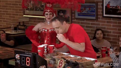Woman in Red Corset and Man in Red Shirt Eating Pizza