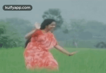 Woman in Red Dress Dancing in Green Field