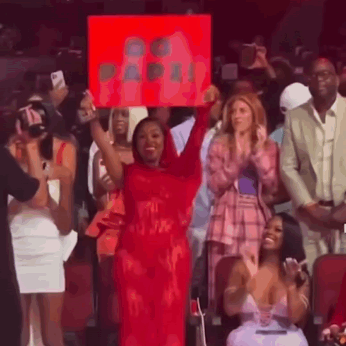 Woman in Red Dress Holding Sign at Concert