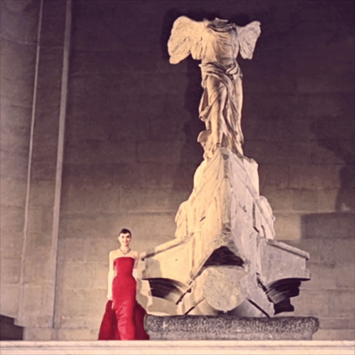 Woman In Red Dress Next To Statue GIF