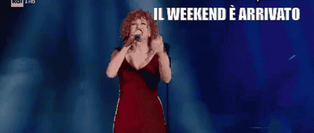 Woman In Red Dress Singing Into Microphone Il Weekend E Arrivato Che Sia Benedetto GIF