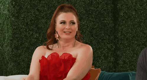 Woman In Red Dress Smiling On Couch GIF